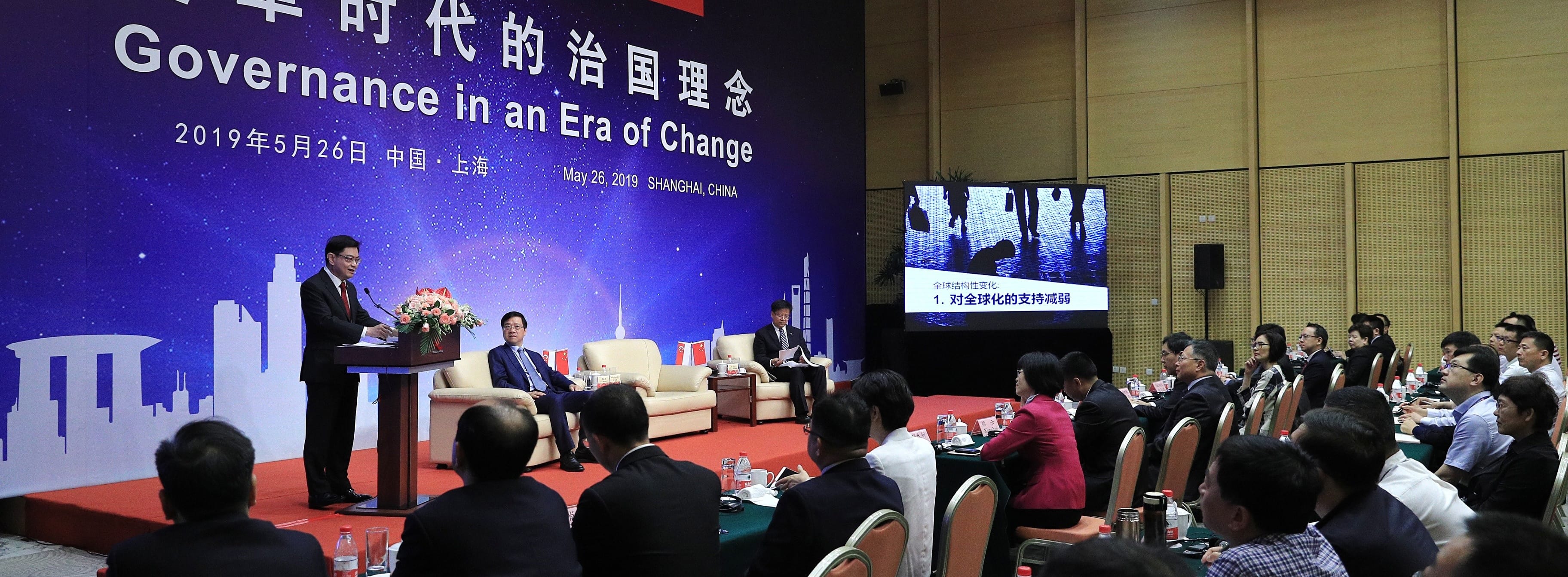 Audience listens to speaker at podium. Screen reads "Governance in an Era of Change."